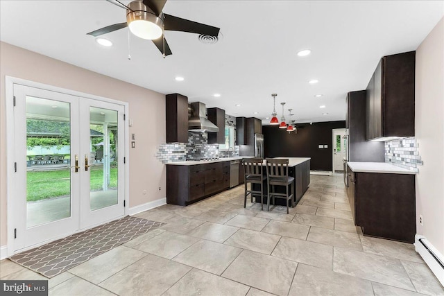 136 Schoolhouse Ln, Glen Mills, PA 19342 - kitchen with wall chimney exhaust hood, light countertops, baseboard heating, dark brown cabinetry, and tasteful backsplash