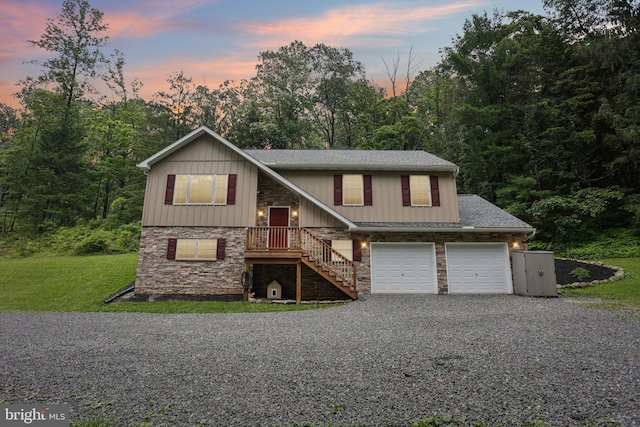 1442 Peacock Ln, Hellertown, PA 18055 - raised ranch with gravel driveway, stone siding, roof with shingles, a front yard, and a garage
