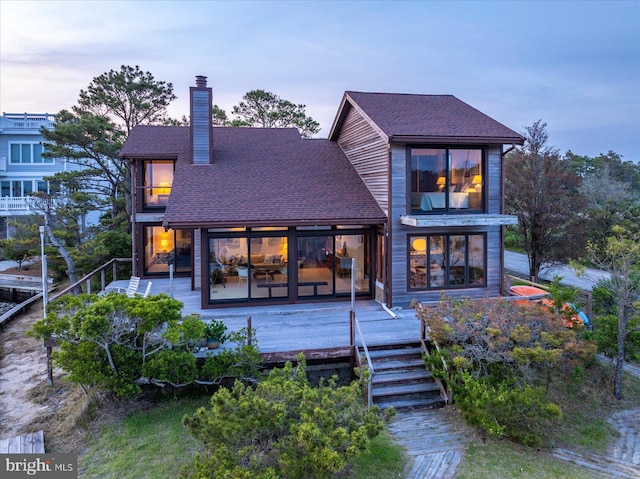 35197 Hassell Ave, Bethany Beach, DE 19930 - back of house at dusk featuring a chimney, a wooden deck, and roof with shingles