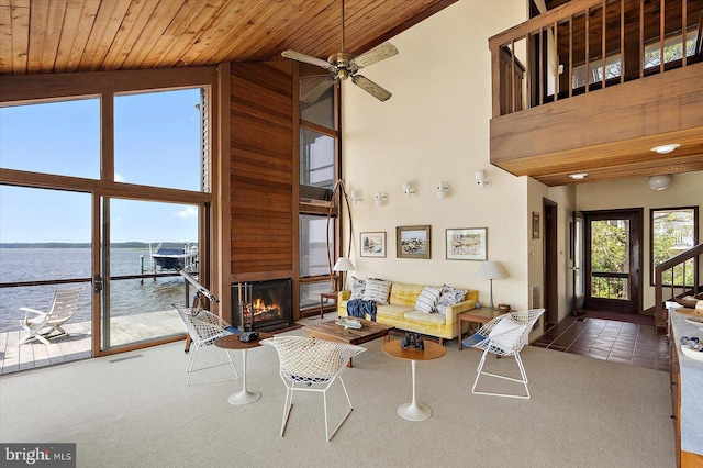 35197 Hassell Ave, Bethany Beach, DE 19930 - tiled living area featuring a water view, high vaulted ceiling, a glass covered fireplace, carpet floors, and a ceiling fan