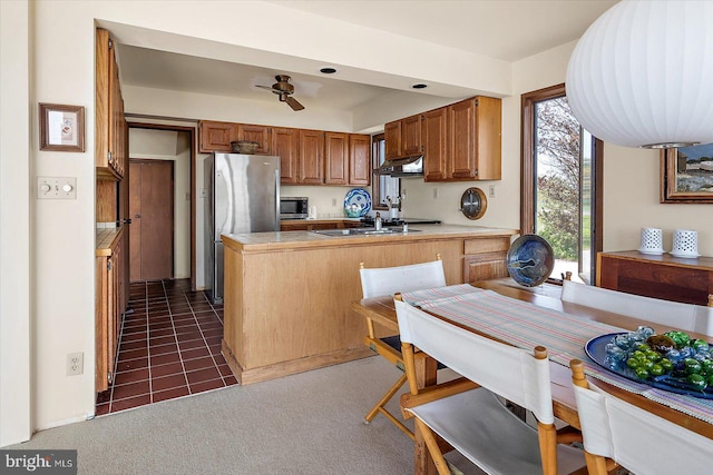 35197 Hassell Ave, Bethany Beach, DE 19930 - kitchen featuring stainless steel appliances, a peninsula, under cabinet range hood, brown cabinets, and light countertops