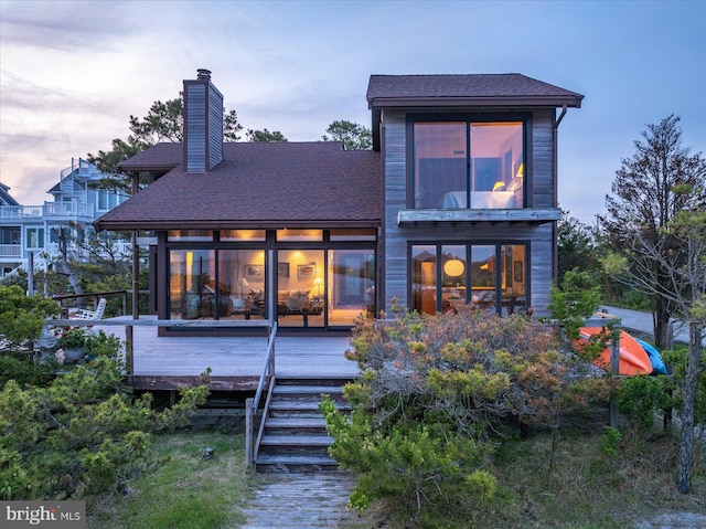 35197 Hassell Ave, Bethany Beach, DE 19930 - back of property at dusk with a chimney, a wooden deck, and a shingled roof