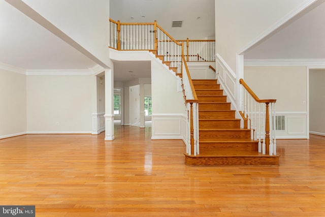 7412 Kallenburg Ct, Manassas, VA 20111 - stairs featuring wood finished floors, a decorative wall, crown molding, a towering ceiling, and wainscoting