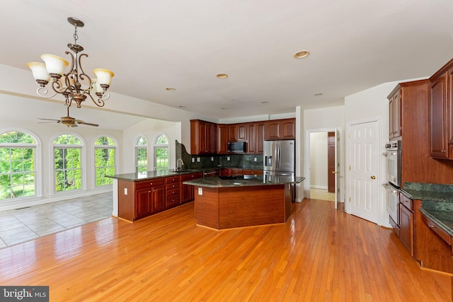 7412 Kallenburg Ct, Manassas, VA 20111 - kitchen featuring appliances with stainless steel finishes, decorative backsplash, a center island, a chandelier, and a ceiling fan