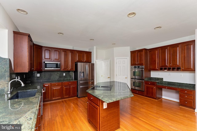 7412 Kallenburg Ct, Manassas, VA 20111 - kitchen featuring appliances with stainless steel finishes, light wood-type flooring, a kitchen island, decorative backsplash, and reddish brown cabinets