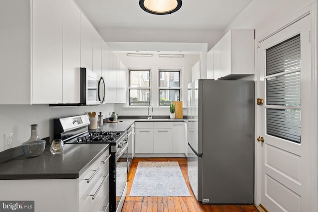 828 Mercer St, Philadelphia, PA 19125 - kitchen featuring stainless steel appliances, dark countertops, hardwood / wood-style floors, and white cabinetry