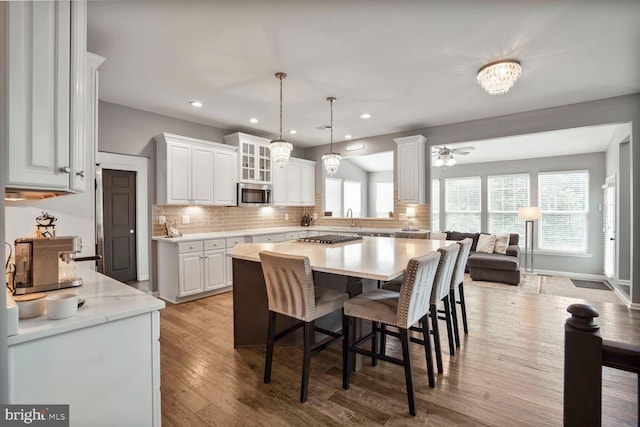 14401 Chalfont Dr, Haymarket, VA 20169 - kitchen with stainless steel appliances, white cabinets, tasteful backsplash, a breakfast bar area, and glass insert cabinets