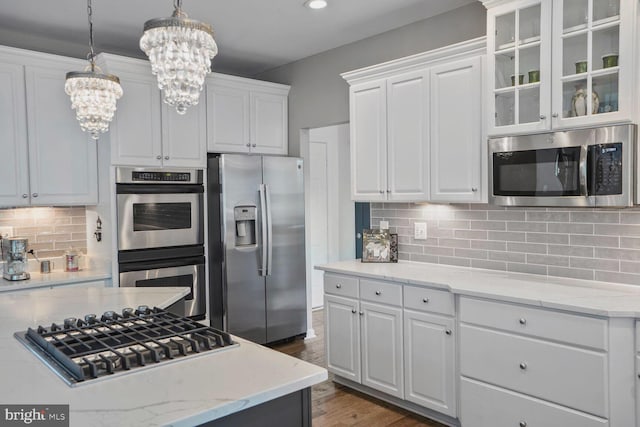 14401 Chalfont Dr, Haymarket, VA 20169 - kitchen featuring appliances with stainless steel finishes, a chandelier, white cabinets, glass insert cabinets, and decorative backsplash