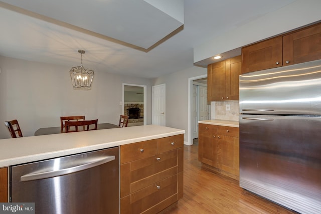 561 Nottingham Dr, Yardley, PA 19067 - kitchen featuring appliances with stainless steel finishes, light wood-type flooring, light countertops, brown cabinets, and a chandelier