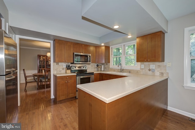 561 Nottingham Dr, Yardley, PA 19067 - kitchen with appliances with stainless steel finishes, brown cabinetry, hardwood / wood-style floors, tasteful backsplash, and recessed lighting