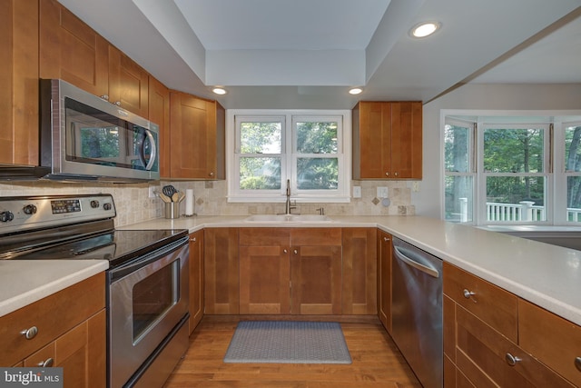 561 Nottingham Dr, Yardley, PA 19067 - kitchen featuring appliances with stainless steel finishes, light wood-style flooring, decorative backsplash, light countertops, and brown cabinetry