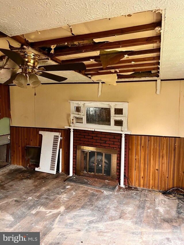 518 Ingleside Ave, Baltimore, MD 21228 - unfurnished living room with wainscoting, a ceiling fan, wooden walls, a fireplace, and a textured ceiling