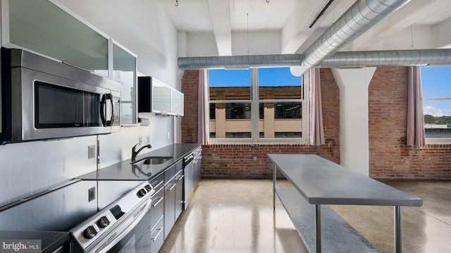 444 N 4th St Unit 401, Philadelphia, PA 19123 - kitchen featuring stainless steel appliances, brick wall, dark countertops, glass insert cabinets, and modern cabinets