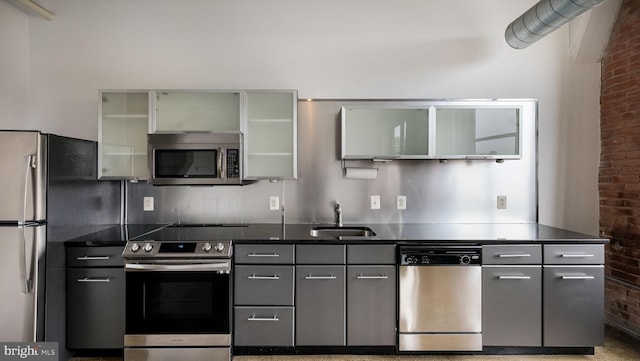 444 N 4th St Unit 401, Philadelphia, PA 19123 - kitchen featuring appliances with stainless steel finishes, brick wall, dark countertops, gray cabinetry, and glass insert cabinets