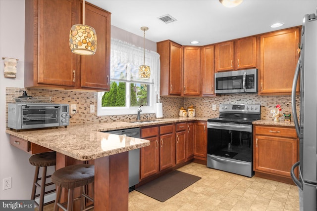 1122 N 14th St, Allentown, PA 18102 - kitchen featuring stainless steel appliances, a peninsula, light stone counters, and brown cabinetry