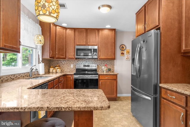 1122 N 14th St, Allentown, PA 18102 - kitchen featuring stainless steel appliances, brown cabinetry, tasteful backsplash, light stone counters, and a peninsula