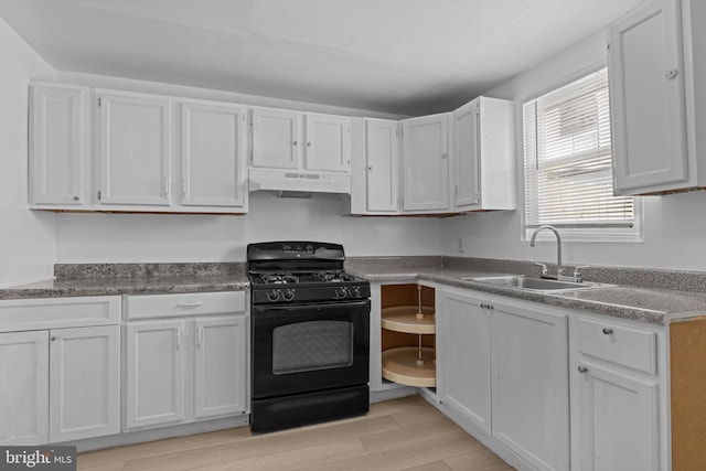 kitchen with black gas stove, under cabinet range hood, light wood finished floors, and white cabinetry