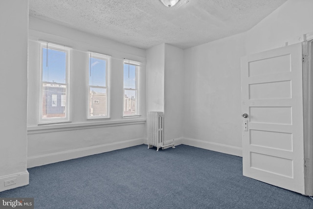 unfurnished room with dark carpet, radiator, and a textured ceiling