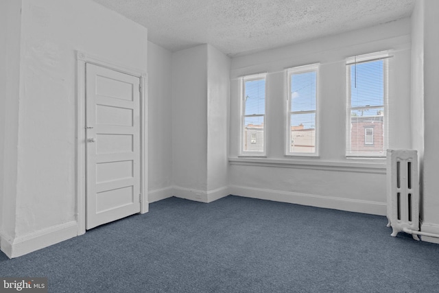 empty room with dark carpet and a textured ceiling