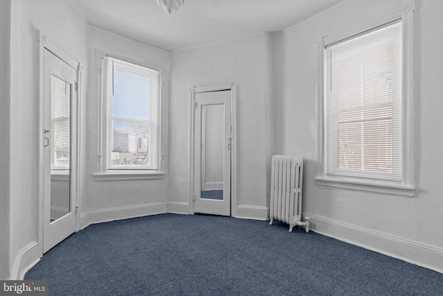 spare room featuring radiator heating unit and dark carpet