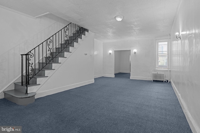 basement featuring radiator, stairway, carpet flooring, and a textured ceiling