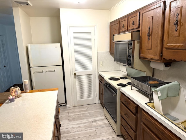 170 E Holly Ln, Tuckerton, NJ 08087 - kitchen with white appliances, light countertops, light wood-style floors, and brown cabinets
