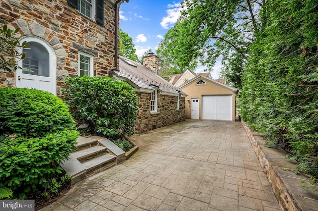6316 Mossway, Baltimore, MD 21212 - view of home's exterior with stone siding, an outbuilding, a garage, and a chimney