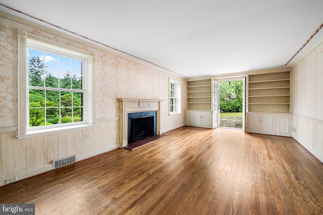 6316 Mossway, Baltimore, MD 21212 - unfurnished living room with wallpapered walls, a fireplace, wood finished floors, healthy amount of natural light, and built in shelves