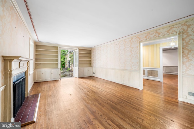 6316 Mossway, Baltimore, MD 21212 - unfurnished living room featuring a tile fireplace, wallpapered walls, built in shelves, wainscoting, and wood finished floors