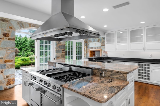 6316 Mossway, Baltimore, MD 21212 - kitchen featuring island exhaust hood, stainless steel gas range, white cabinets, dark stone counters, and wood finished floors
