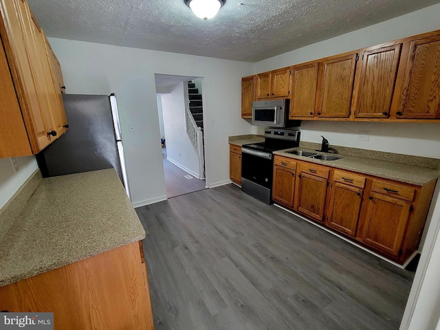 110 N Mulberry St, Hagerstown, MD 21740 - kitchen with appliances with stainless steel finishes, brown cabinets, dark wood-type flooring, a textured ceiling, and light countertops