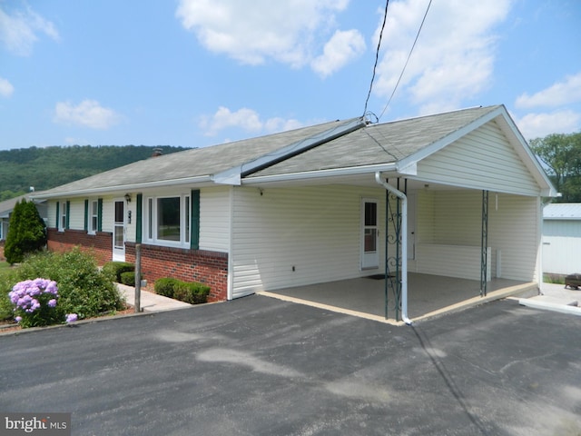 201 Cherry St, Millheim, PA 16854 - view of front of house featuring driveway, brick siding, roof mounted solar panels, a carport, and a shingled roof