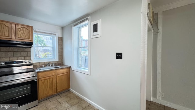 3436 D St, Philadelphia, PA 19134 - kitchen featuring stainless steel range with electric stovetop, under cabinet range hood, tasteful backsplash, brown cabinets, and light tile patterned flooring
