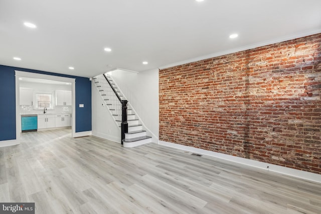 3287 Edgemont St, Philadelphia, PA 19134 - unfurnished living room featuring stairway, light wood finished floors, brick wall, and recessed lighting