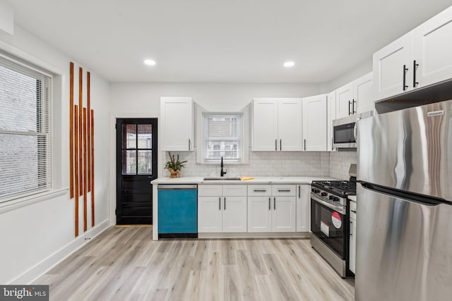 3287 Edgemont St, Philadelphia, PA 19134 - kitchen with stainless steel appliances, light wood finished floors, white cabinetry, tasteful backsplash, and light countertops