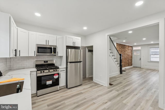 3287 Edgemont St, Philadelphia, PA 19134 - kitchen with stainless steel appliances, light stone countertops, light wood finished floors, tasteful backsplash, and white cabinetry