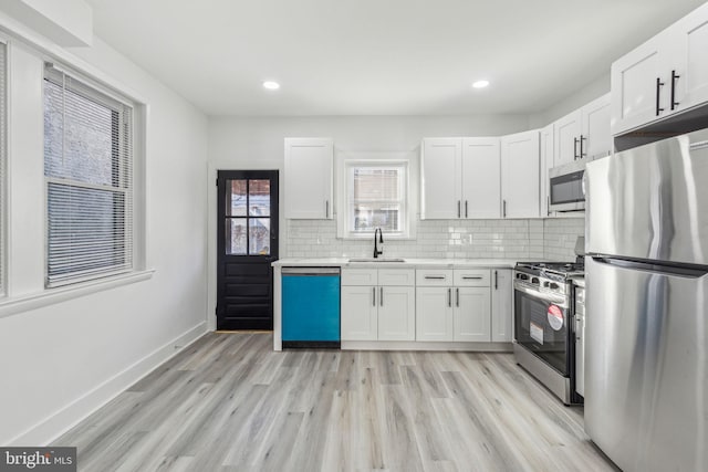 3287 Edgemont St, Philadelphia, PA 19134 - kitchen with stainless steel appliances, light countertops, white cabinets, light wood-type flooring, and recessed lighting