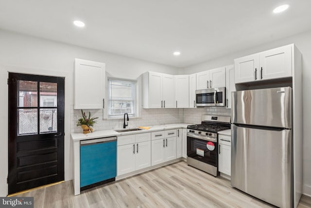 3287 Edgemont St, Philadelphia, PA 19134 - kitchen with stainless steel appliances, light countertops, white cabinets, light wood finished floors, and backsplash