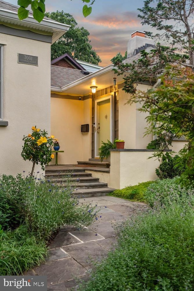 7001 Sycamore Ave, Takoma Park, MD 20912 - exterior entry at dusk with stucco siding, a shingled roof, and a chimney