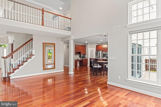 42066 Fiddlehead Pl, Aldie, VA 20105 - living room with a high ceiling, light wood-style flooring, stairs, ornamental molding, and recessed lighting