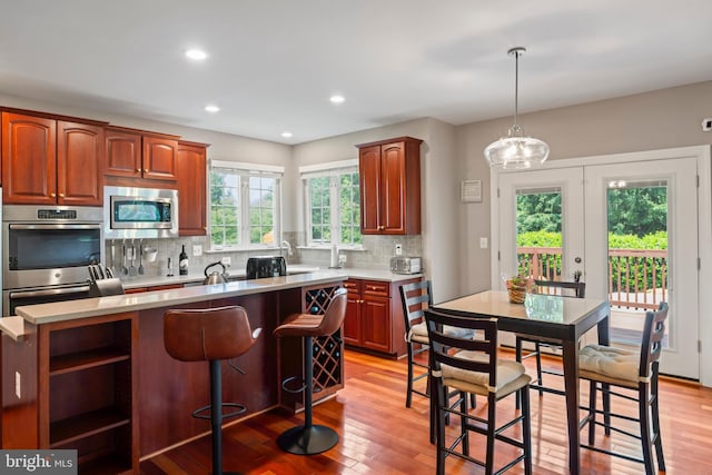42066 Fiddlehead Pl, Aldie, VA 20105 - kitchen with appliances with stainless steel finishes, a kitchen island, backsplash, light countertops, and light wood-style floors