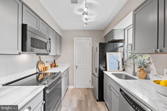 2050 N Calvert St Unit 410, Arlington, VA 22201 - kitchen with appliances with stainless steel finishes, gray cabinetry, backsplash, and light stone countertops