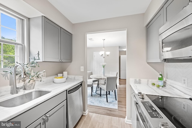 2050 N Calvert St Unit 410, Arlington, VA 22201 - kitchen featuring stainless steel appliances, gray cabinets, light wood-type flooring, and light stone counters