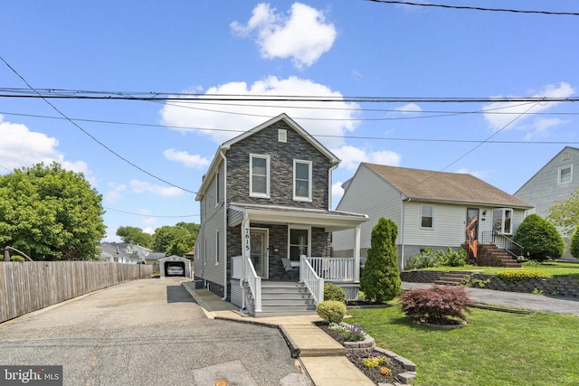 7615 Belmont Ave, Baltimore, MD 21224 - view of front of home with stone siding, a porch, asphalt driveway, and an outdoor structure