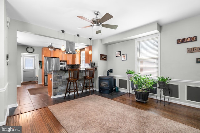 7615 Belmont Ave, Baltimore, MD 21224 - living room with a wood stove, plenty of natural light, a ceiling fan, and dark wood finished floors