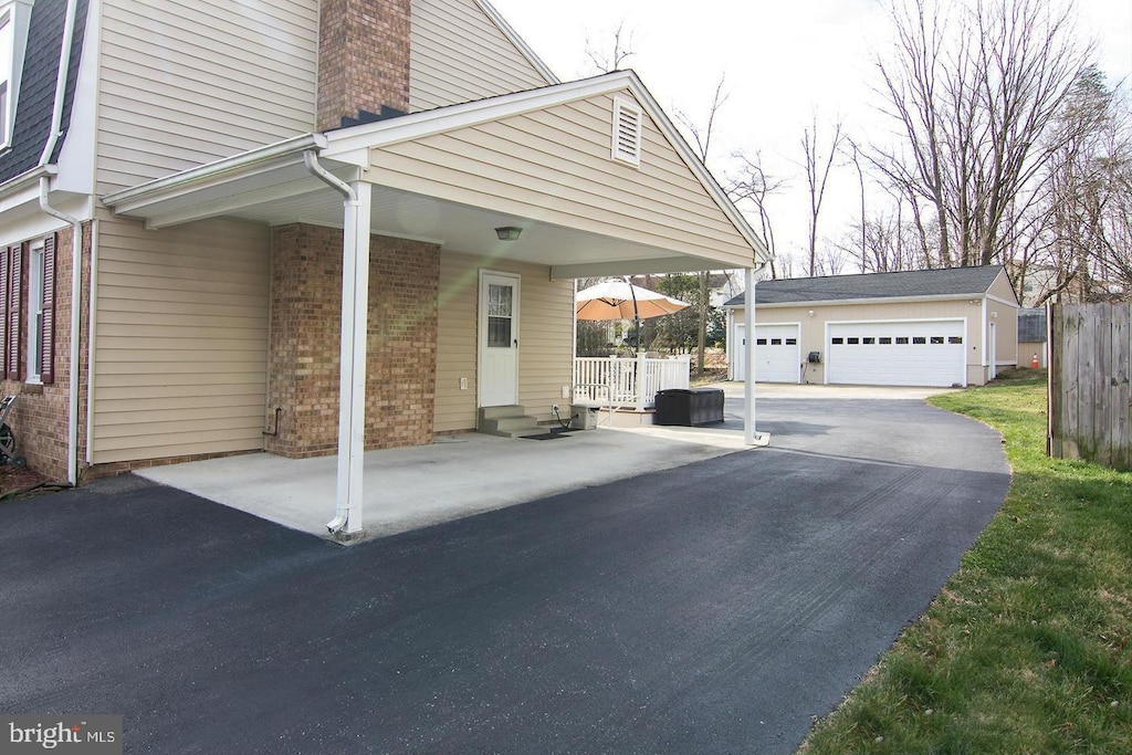 12008 Montague Dr, Laurel, MD 20708 - view of home's exterior featuring an outdoor structure, brick siding, a garage, and a chimney