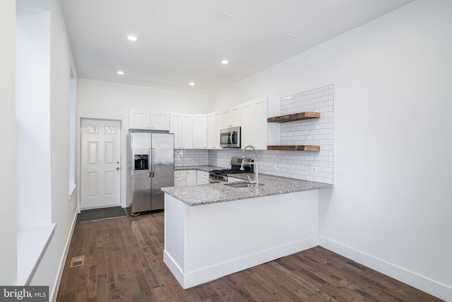 1737 N 28th St, Philadelphia, PA 19121 - kitchen featuring stainless steel appliances, a peninsula, open shelves, light stone counters, and dark wood-type flooring