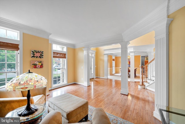 43146 Scenic Creek Way, Leesburg, VA 20176 - living room with decorative columns, crown molding, light wood-style floors, and stairway