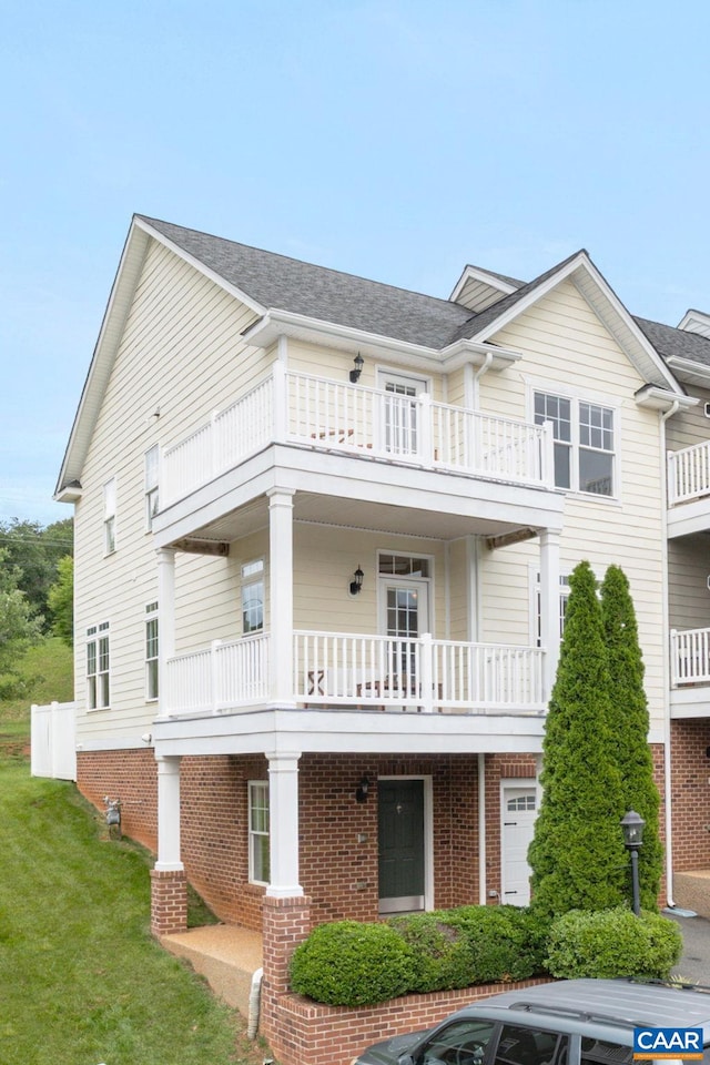 2126 Sundown Pl, Charlottesville, VA 22911 - view of front of house with a balcony, brick siding, a front yard, and a shingled roof