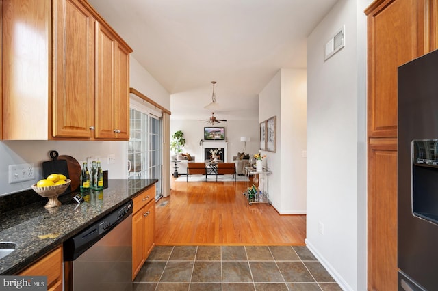 1201 Preserve Ln, Fredericksburg, VA 22401 - kitchen with dishwasher, a fireplace, dark stone countertops, a ceiling fan, and brown cabinets